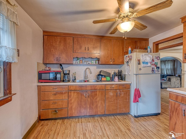 kitchen featuring light countertops, a ceiling fan, a sink, light wood-type flooring, and freestanding refrigerator
