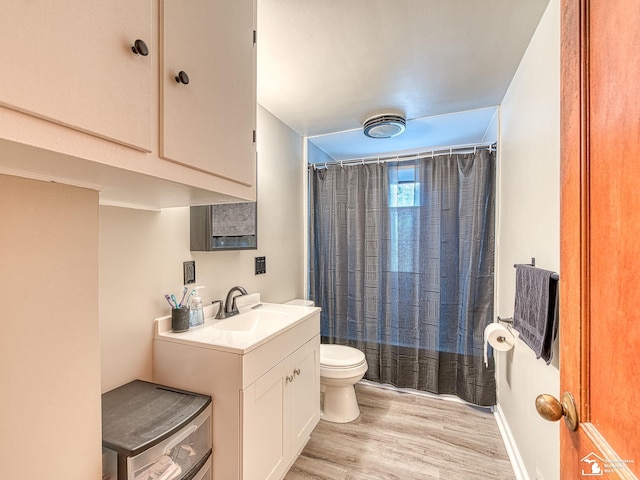 bathroom featuring baseboards, toilet, wood finished floors, curtained shower, and vanity