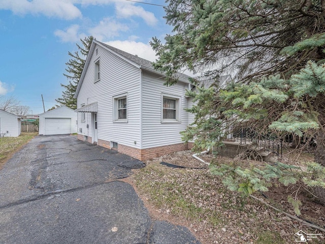 view of side of property with an outdoor structure, aphalt driveway, and a detached garage