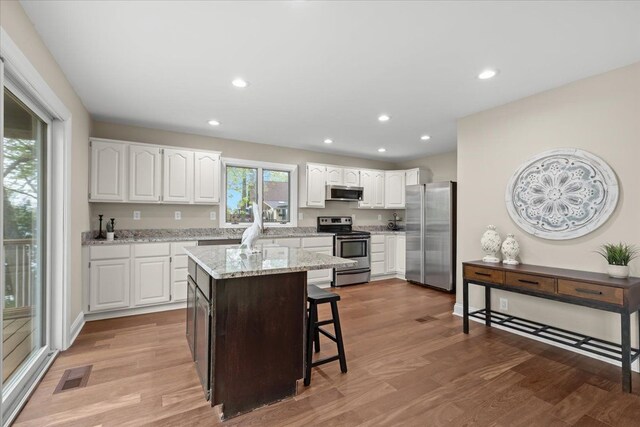 3155 Ridge Rd, White Lake, MI 48383 - kitchen with appliances with stainless steel finishes, white cabinets, light wood-style flooring, recessed lighting, and light stone countertops