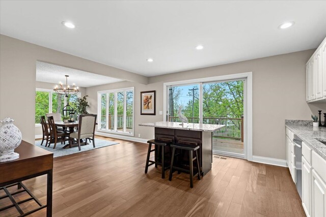 3155 Ridge Rd, White Lake, MI 48383 - kitchen featuring baseboards, white cabinetry, light wood-style floors, a chandelier, and a breakfast bar area