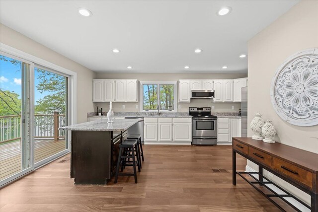 3155 Ridge Rd, White Lake, MI 48383 - kitchen with stainless steel appliances, recessed lighting, white cabinetry, wood finished floors, and light stone counters