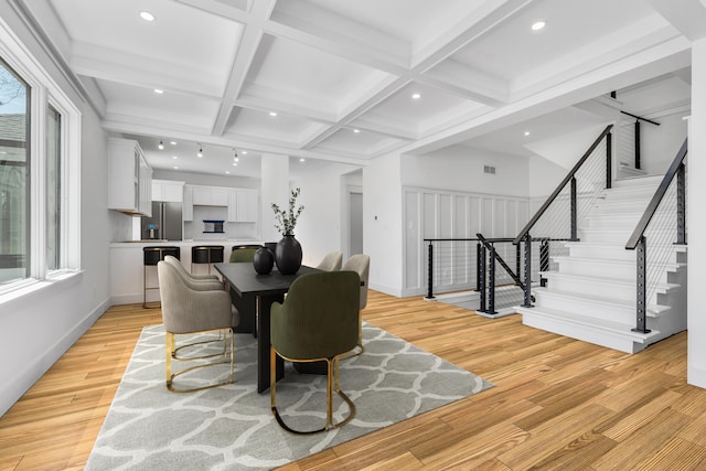 dining room with light wood finished floors, stairs, coffered ceiling, and a healthy amount of sunlight
