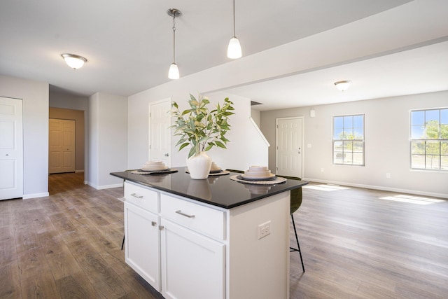 13662 Oasis Ave, Holland, MI 49424 - kitchen with dark countertops, wood finished floors, pendant lighting, white cabinetry, and a kitchen island
