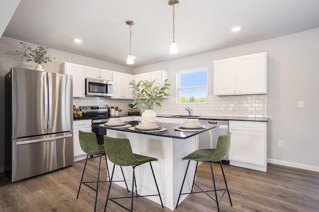 13662 Oasis Ave, Holland, MI 49424 - kitchen featuring appliances with stainless steel finishes, a kitchen bar, white cabinetry, dark countertops, and backsplash