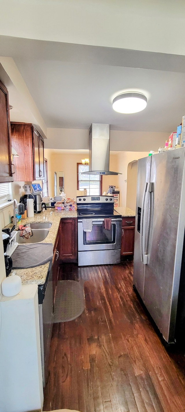 kitchen featuring stainless steel appliances, island range hood, dark wood-style floors, a sink, and light stone countertops
