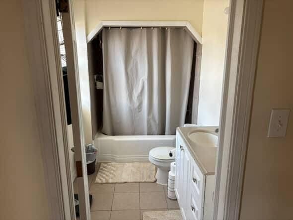 bathroom featuring tile patterned flooring, vanity, toilet, and shower / tub combo with curtain