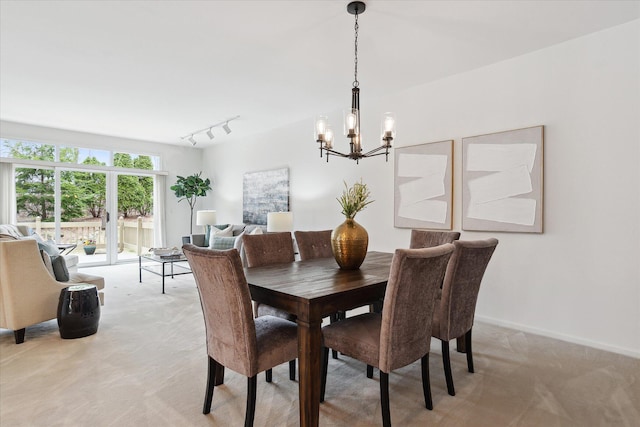 dining room with baseboards, track lighting, a notable chandelier, and light colored carpet