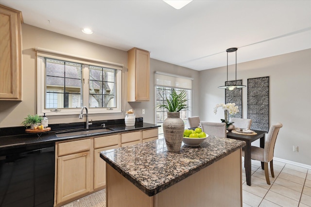 kitchen featuring a sink, light brown cabinetry, dishwasher, a center island, and dark stone counters