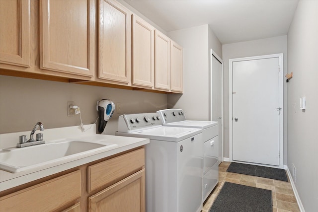 laundry area featuring baseboards, cabinet space, a sink, and washer and clothes dryer