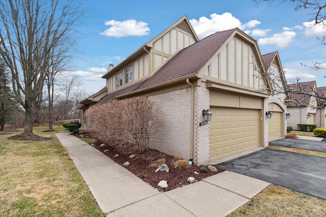 view of side of home featuring driveway, a chimney, an attached garage, brick siding, and a shingled roof