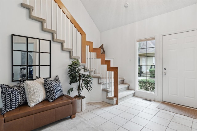 entrance foyer featuring stairs, vaulted ceiling, and light tile patterned floors