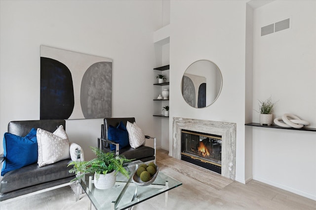 living room with baseboards, visible vents, a high end fireplace, and built in features