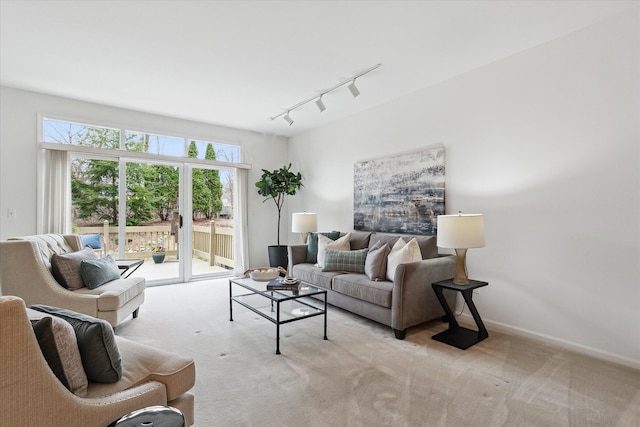 carpeted living area with rail lighting and baseboards