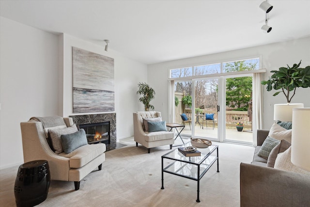 living area with a high end fireplace, carpet flooring, and rail lighting