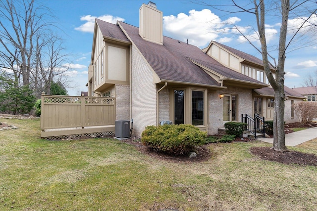 view of side of home with central air condition unit, brick siding, a shingled roof, a yard, and a chimney