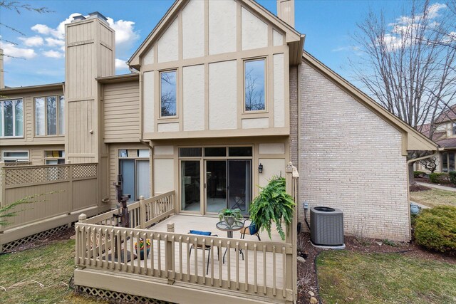 back of house with stucco siding, central air condition unit, a deck, and a chimney