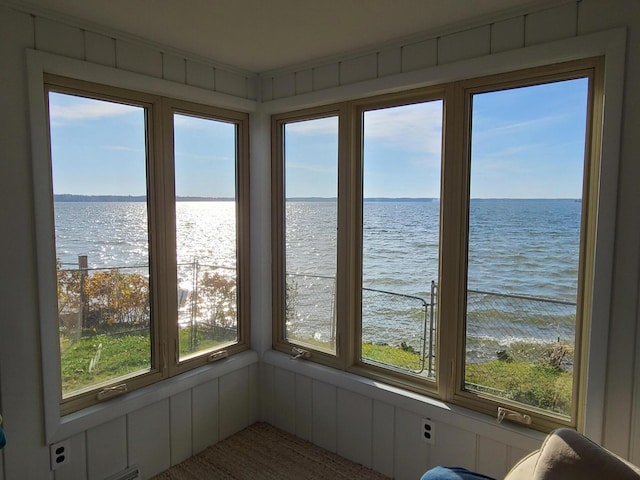 unfurnished sunroom with a wealth of natural light, a water view, and a decorative wall