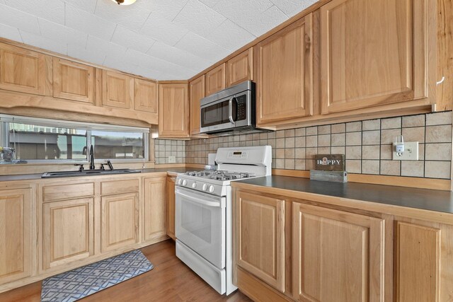 kitchen featuring stainless steel microwave, a sink, white gas stove, and light brown cabinetry