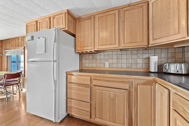 kitchen with light brown cabinets, dark countertops, and freestanding refrigerator