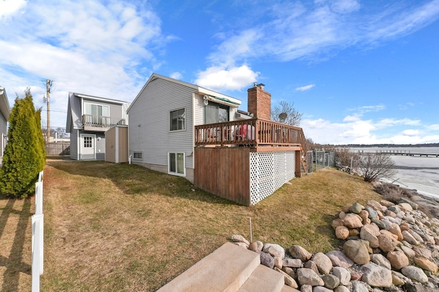 back of house with a lawn, a chimney, and a wooden deck