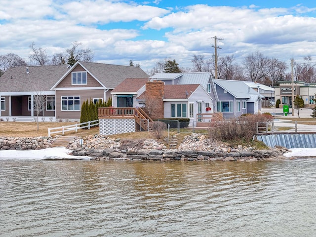 view of dock with a deck with water view, fence, and a residential view