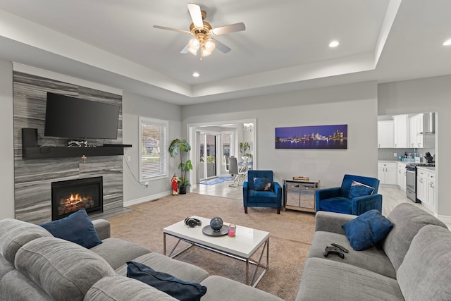 living room with recessed lighting, a ceiling fan, light colored carpet, and a raised ceiling