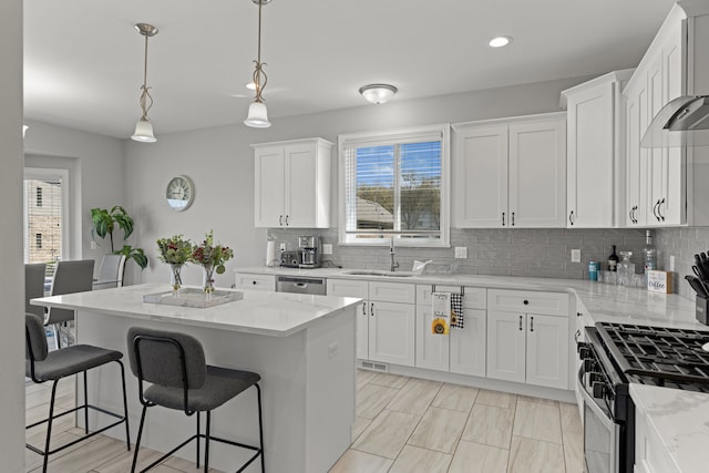 kitchen featuring white cabinets, a sink, a kitchen breakfast bar, a center island, and tasteful backsplash