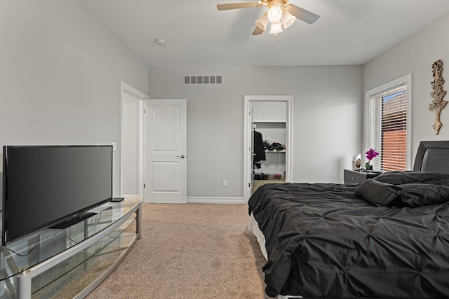 bedroom featuring a walk in closet, carpet, a ceiling fan, baseboards, and visible vents