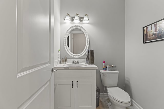 bathroom with toilet, wood finished floors, and vanity