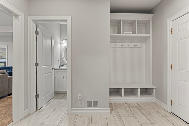 mudroom with visible vents, a sink, and baseboards