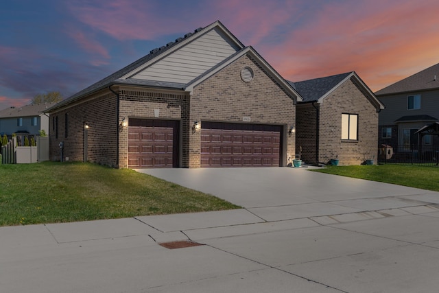 ranch-style home featuring a lawn, an attached garage, driveway, and brick siding