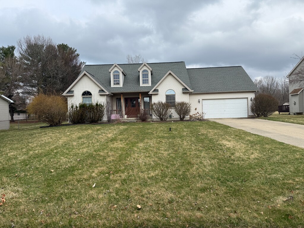 view of front of home featuring a porch, driveway, a garage, and a front lawn