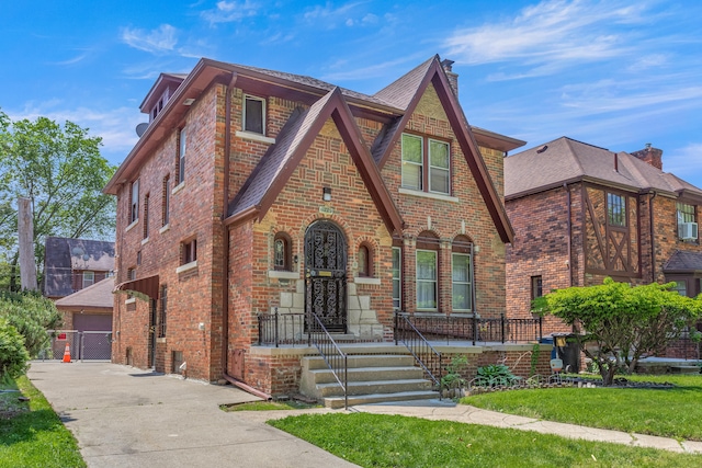 8735 Marygrove Dr, Detroit, MI 48221 - tudor-style house featuring brick siding, a front yard, an outdoor structure, and roof with shingles