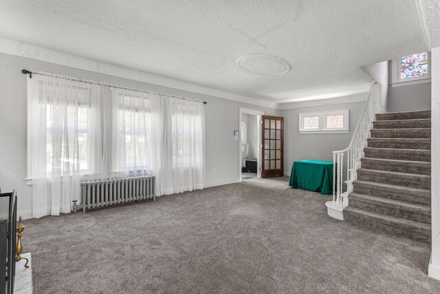 8735 Marygrove Dr, Detroit, MI 48221 - unfurnished living room featuring a textured ceiling, radiator heating unit, carpet flooring, stairs, and baseboards