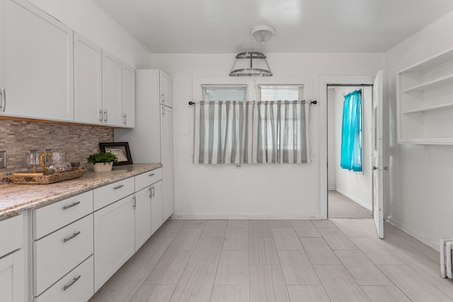 8735 Marygrove Dr, Detroit, MI 48221 - kitchen with backsplash, baseboards, white cabinetry, and light stone counters