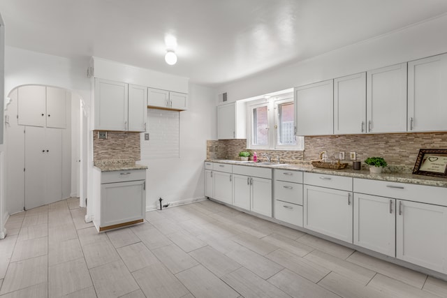 8735 Marygrove Dr, Detroit, MI 48221 - kitchen featuring a sink, decorative backsplash, arched walkways, and light stone counters