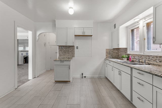 8735 Marygrove Dr, Detroit, MI 48221 - kitchen featuring arched walkways, visible vents, a sink, baseboards, and backsplash