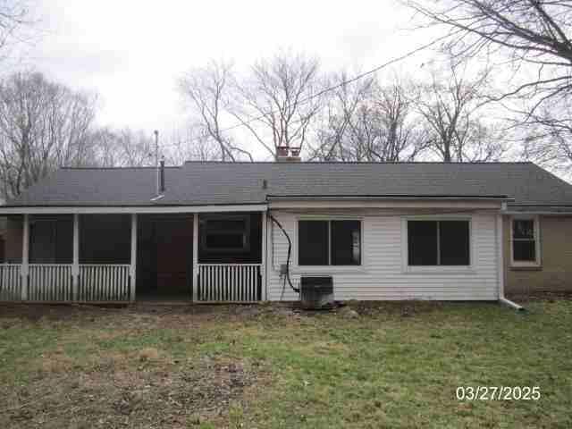 rear view of property featuring central AC unit and a yard