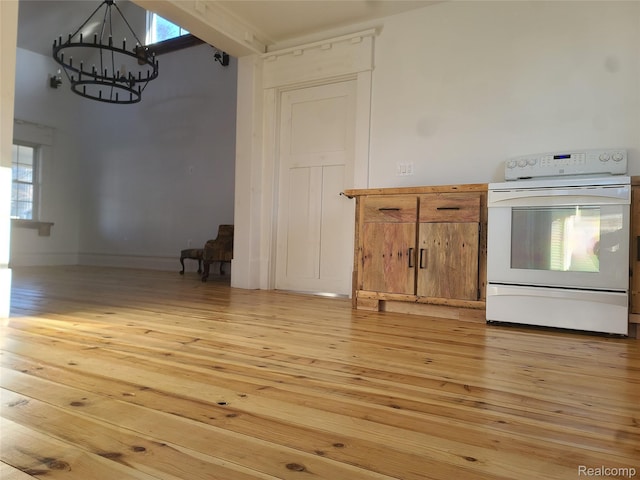 3685 Main St, Akron, MI 48701 - kitchen with electric range, a chandelier, light wood finished floors, and brown cabinets