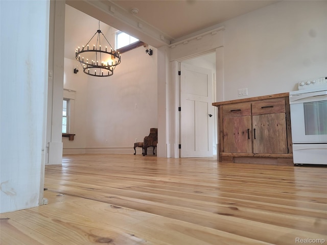 3685 Main St, Akron, MI 48701 - kitchen with electric stove, light wood-type flooring, a chandelier, brown cabinets, and plenty of natural light