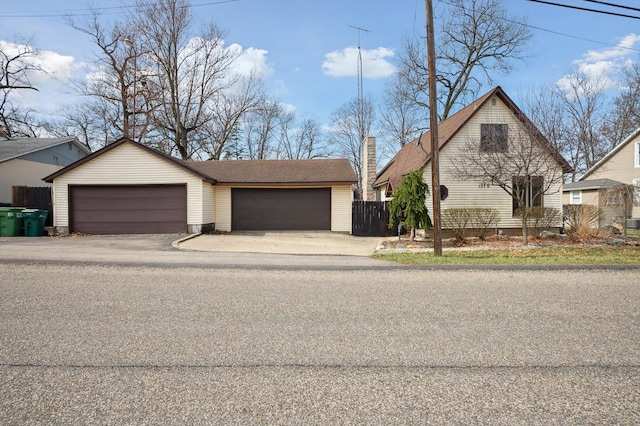 view of front of house featuring a shingled roof, an outdoor structure, fence, and a garage