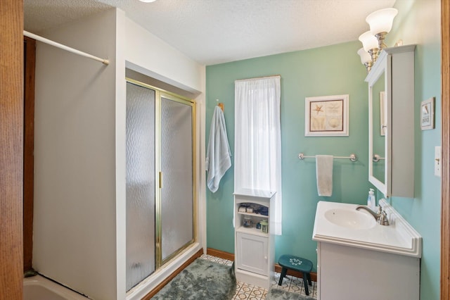 full bath with vanity, a stall shower, and a textured ceiling