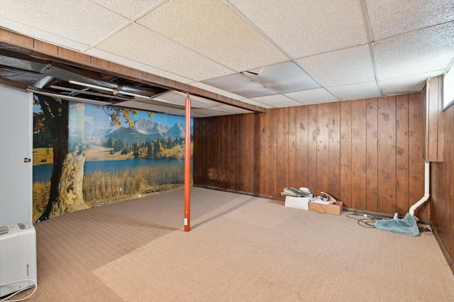 finished below grade area with carpet flooring, wood walls, and a drop ceiling