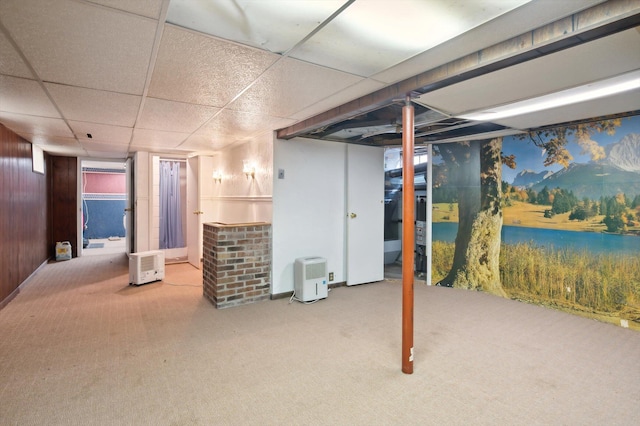 finished basement with wood walls, carpet, and a drop ceiling