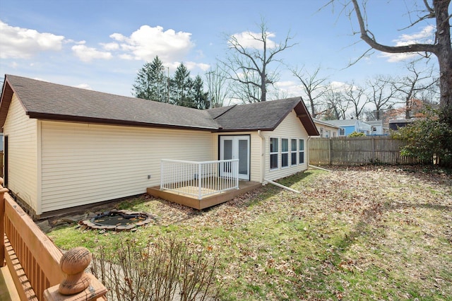 back of property with roof with shingles, a deck, and fence