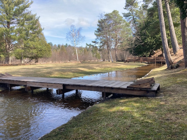view of dock featuring a lawn and a water view