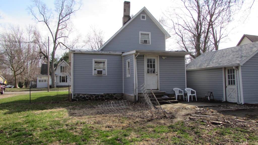 rear view of house featuring cooling unit, a chimney, entry steps, and a yard