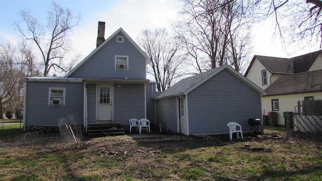 back of house featuring entry steps and a chimney