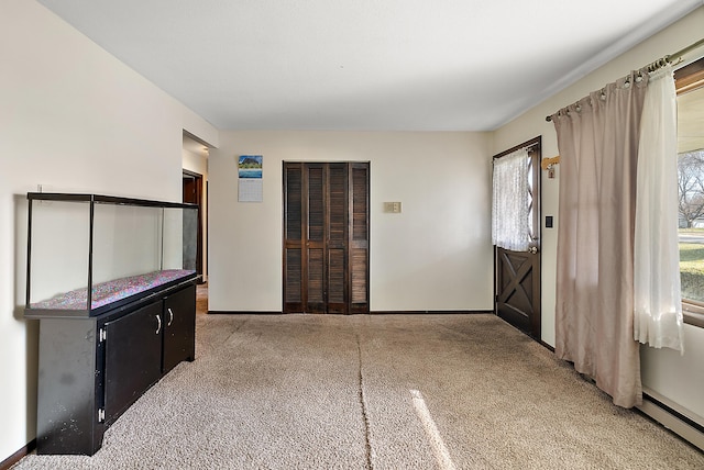 entrance foyer with light carpet, baseboards, and a baseboard heating unit